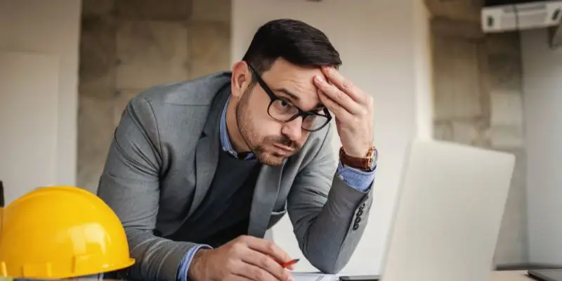 A construction executive looks stressed at his computer over OEM crusher delays