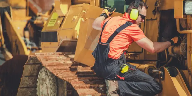 A worker provides crusher maintenance on a large piece of mining machinery