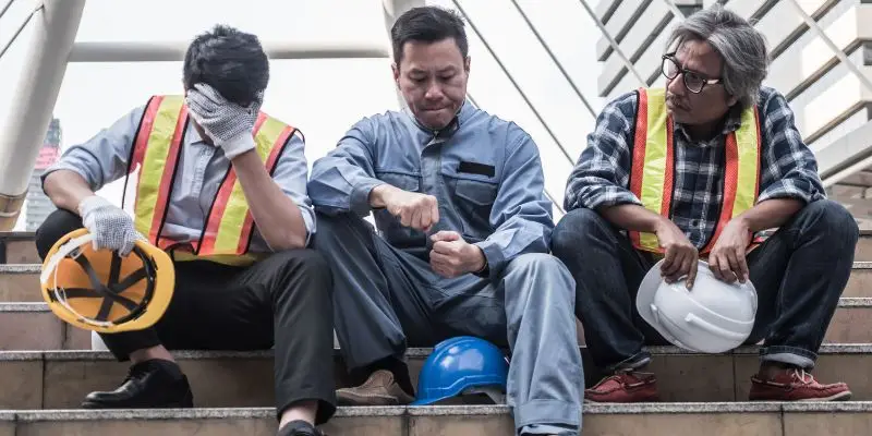 Mine workers and executives sit on steps, frustrated