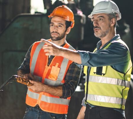 Two workers in hardhats undergo crusher maintenance training