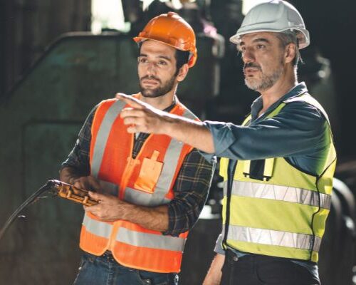 Two workers in hardhats undergo crusher maintenance training