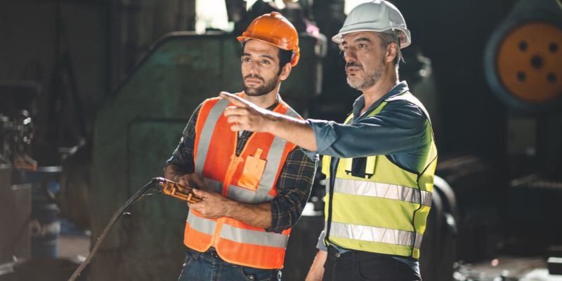 Two workers in hardhats undergo crusher maintenance training