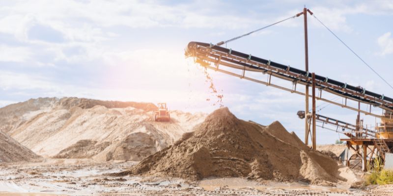 Large machinery at a quarry grinds and drops rock, highlighting cone crusher optimization