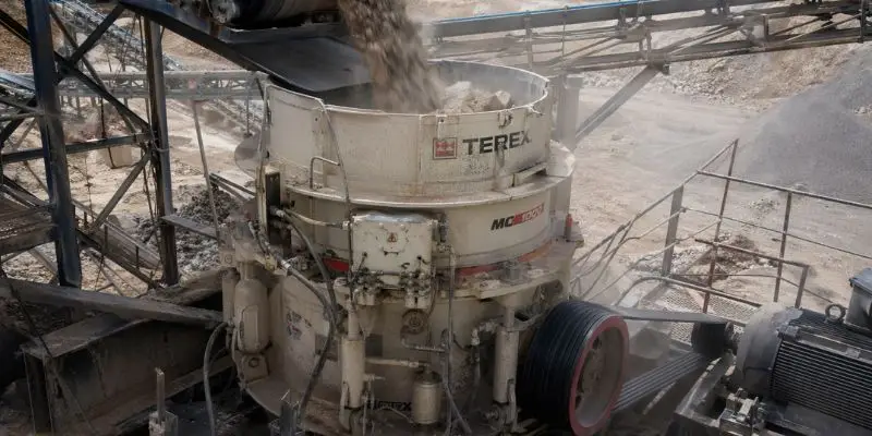 Cone crusher processing material with steady feed and active conveyors, highlighting crusher performance optimization in a working mining operation.