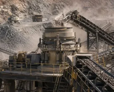 Cone crusher operating at a large mining site with conveyors moving material, supporting efforts to reduce crusher downtime.