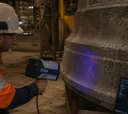 Technician scanning cone crusher mantle and bowl liner with 3D scanner for wear analysis in plant
