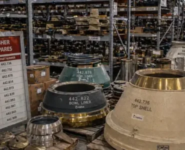 Warehouse stocked with mining crusher parts including mantles, bowl liners, and cone crusher components